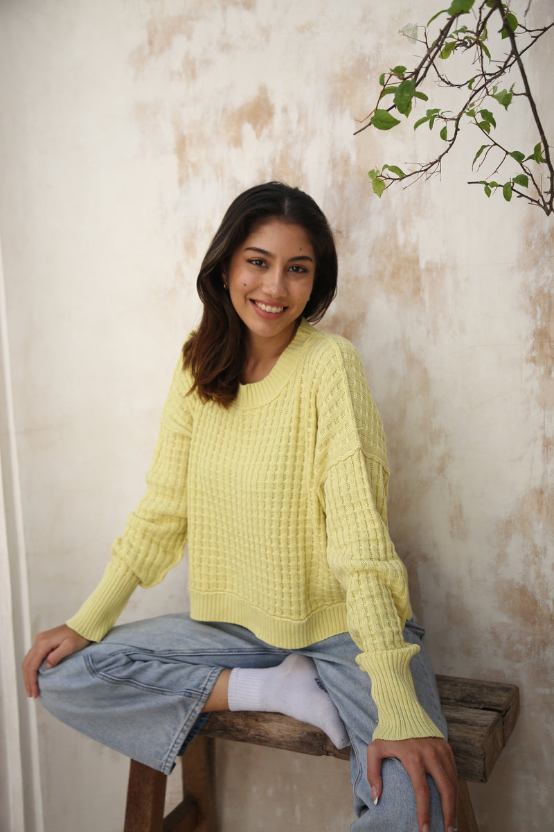 A yellow waffle-knit sweater paired with denim jeans, featuring a relaxed fit and fold-back cuffs. Available at Lemonberry, Aurora, ON